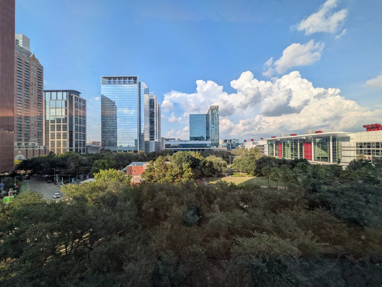 A view of a downtown skyline overlooking an open green park.