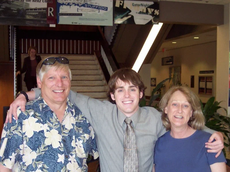 A group photo shows a man, woman, and young man smiling together in what appears to be an airport. The caption identifies them as the author's mom, dad, and himself during his sophomore year of college.